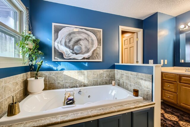 full bathroom featuring vanity, a textured ceiling, and a tub with jets