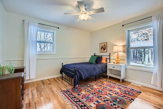 bedroom featuring light wood-style floors, visible vents, and a textured ceiling