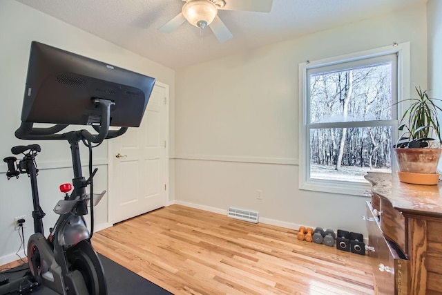 workout area featuring light wood-type flooring, visible vents, ceiling fan, and baseboards