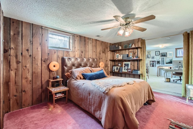 carpeted bedroom with ceiling fan, wooden walls, visible vents, and a textured ceiling