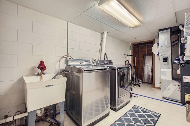 clothes washing area featuring washer and clothes dryer, light floors, heating unit, a sink, and laundry area