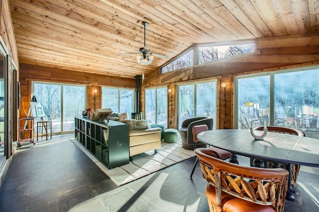 sunroom / solarium featuring wood ceiling, lofted ceiling, a wood stove, and ceiling fan