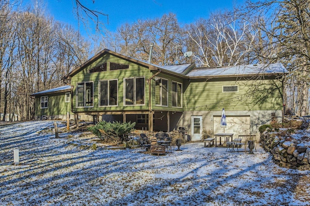 snow covered property with a fire pit and a sunroom