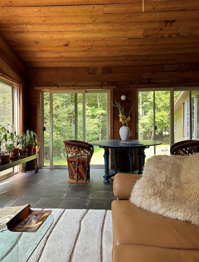 interior space with wooden ceiling, stone tile flooring, and wooden walls