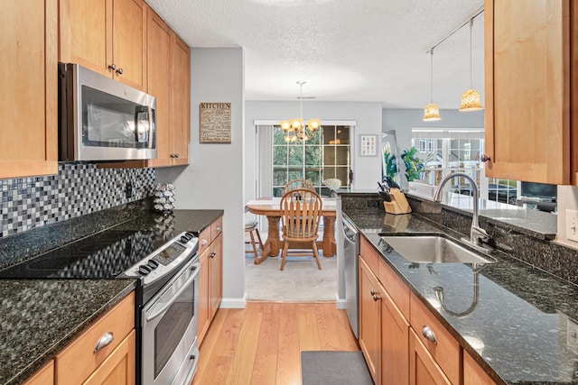 kitchen with light wood-style flooring, a sink, backsplash, stainless steel appliances, and a healthy amount of sunlight