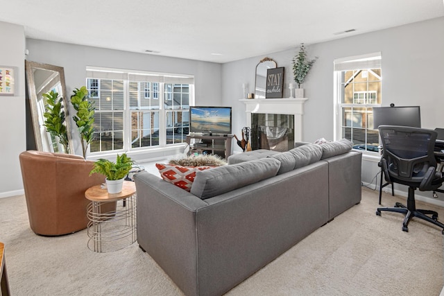 living room with a tiled fireplace, a healthy amount of sunlight, and carpet