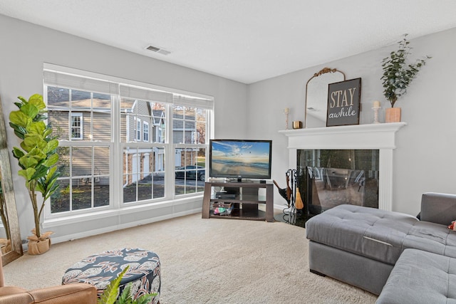 carpeted living area with visible vents, baseboards, a textured ceiling, and a fireplace