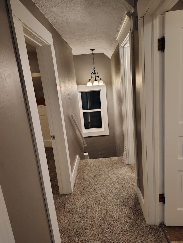 hallway featuring dark carpet, a textured ceiling, and vaulted ceiling