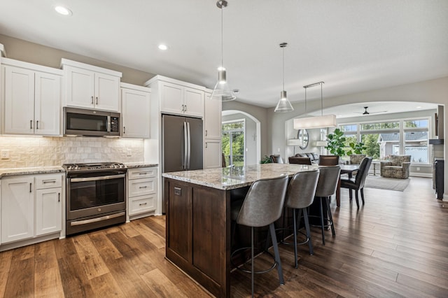 kitchen with appliances with stainless steel finishes, ceiling fan, white cabinets, a center island, and dark hardwood / wood-style floors