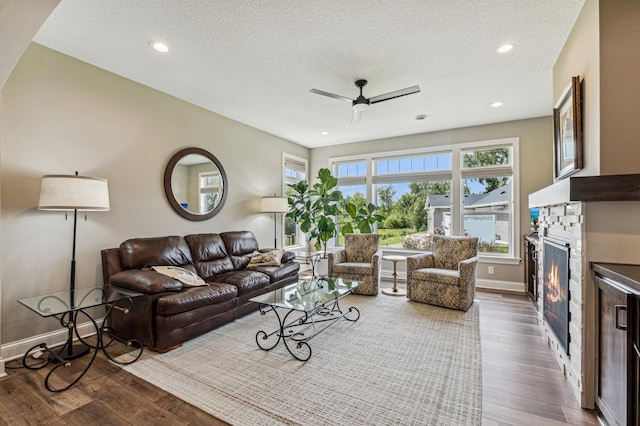 living room with a textured ceiling, ceiling fan, and dark hardwood / wood-style floors