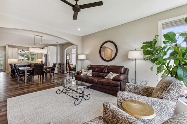 living room featuring plenty of natural light, ceiling fan, and dark wood-type flooring