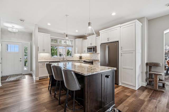 kitchen featuring white cabinetry, sink, stainless steel appliances, dark hardwood / wood-style flooring, and a kitchen island