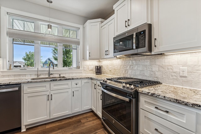 kitchen with sink, hanging light fixtures, stainless steel appliances, dark hardwood / wood-style floors, and white cabinets