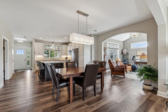 dining room featuring a healthy amount of sunlight, dark wood-type flooring, and a chandelier