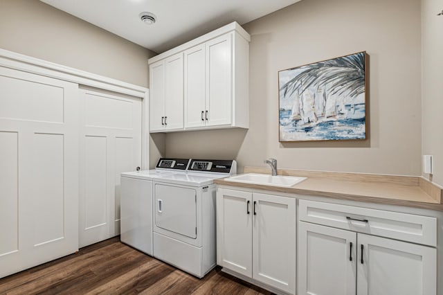 clothes washing area with dark wood-type flooring, sink, cabinets, and washing machine and dryer