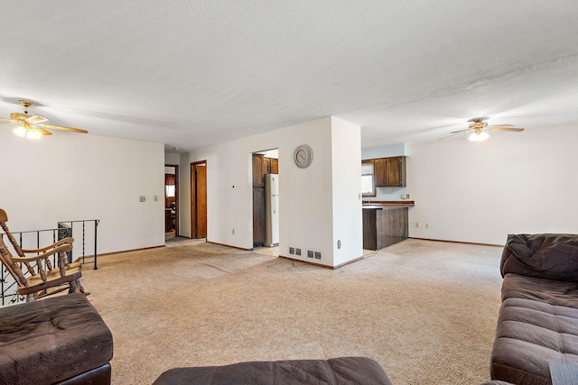 living room featuring ceiling fan, light colored carpet, and a textured ceiling