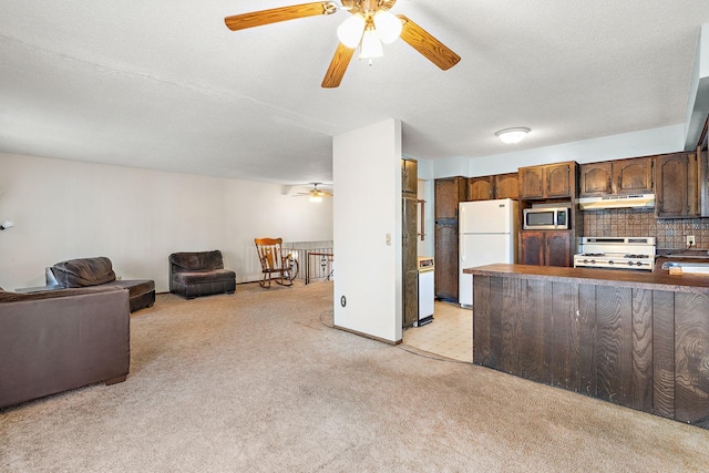 kitchen featuring stainless steel microwave, light carpet, white fridge, and stove