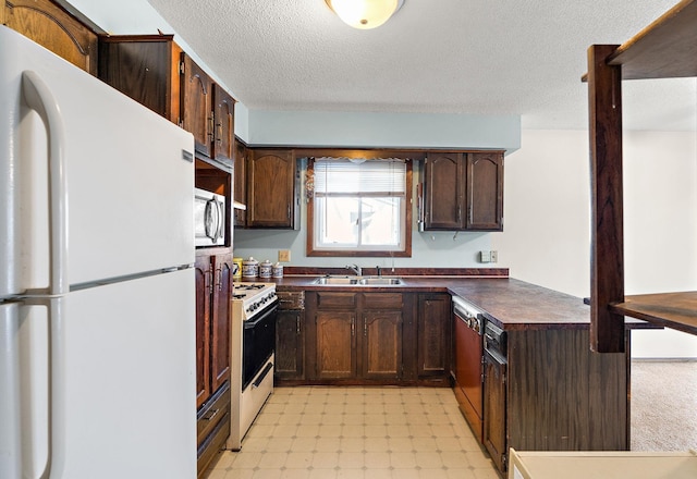 kitchen featuring dark brown cabinetry, sink, white appliances, and a textured ceiling