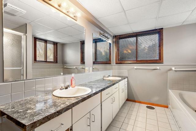 bathroom with plus walk in shower, decorative backsplash, vanity, a drop ceiling, and tile patterned floors