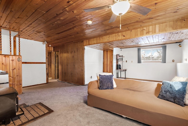 living room with ceiling fan, carpet flooring, wood ceiling, and wood walls