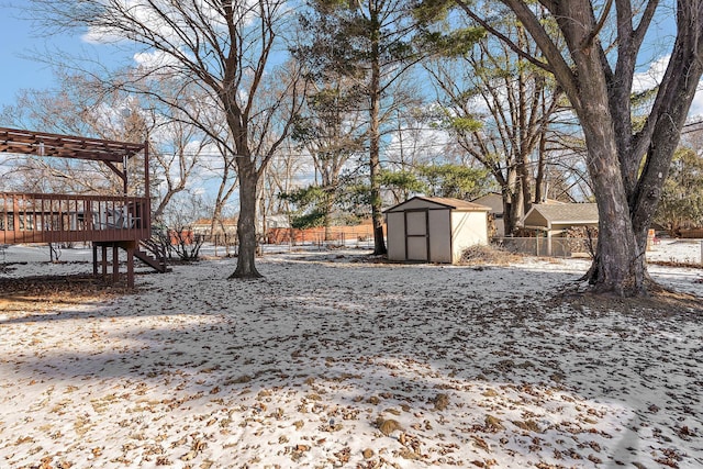 snowy yard with a storage shed and a deck