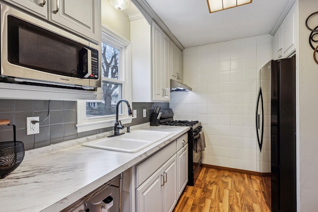 kitchen featuring black appliances, light hardwood / wood-style floors, sink, and a wealth of natural light