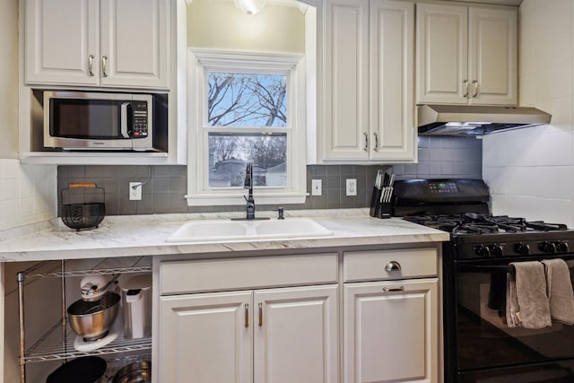 kitchen featuring sink, tasteful backsplash, black range with gas stovetop, light stone counters, and white cabinets