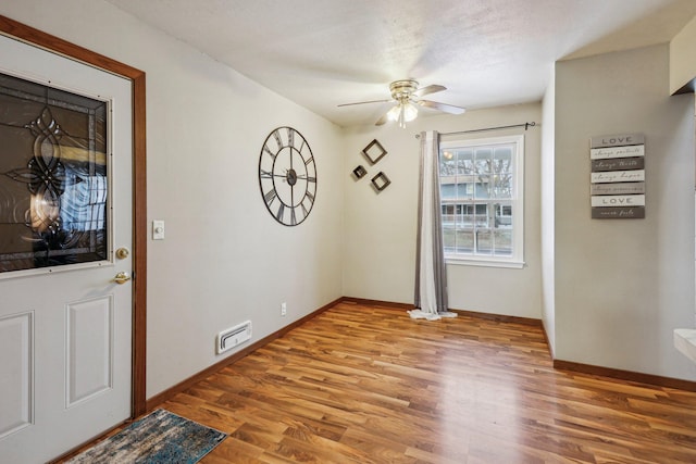 foyer entrance featuring ceiling fan, light hardwood / wood-style flooring, and a textured ceiling