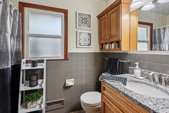 bathroom with vanity, tile walls, and toilet