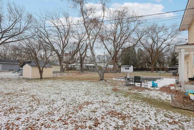 snowy yard featuring a storage unit