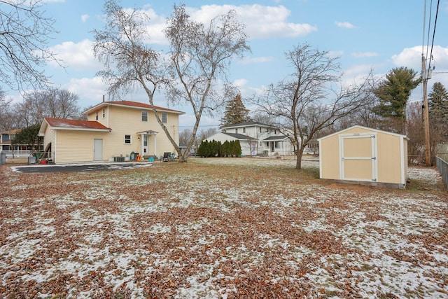 snowy yard featuring a patio area and a storage unit