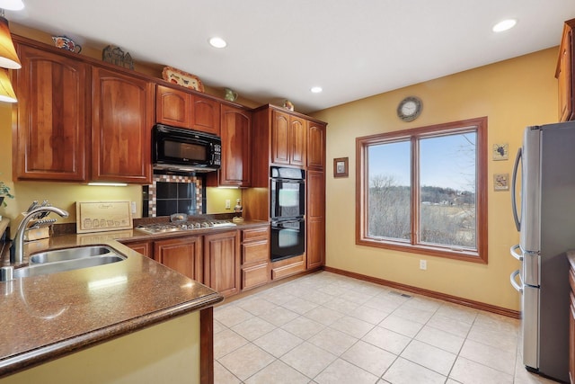 kitchen with sink, light tile patterned floors, dark stone countertops, and black appliances