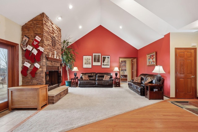 living room featuring vaulted ceiling, light hardwood / wood-style floors, and a stone fireplace