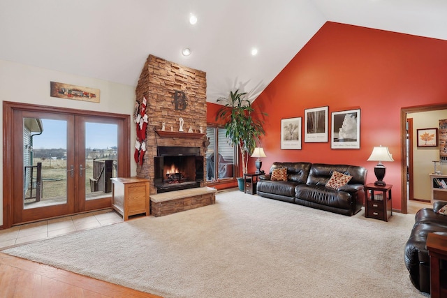 living room featuring french doors, high vaulted ceiling, light carpet, and a stone fireplace