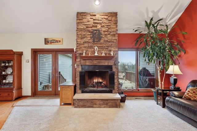 living room featuring french doors, a wealth of natural light, and a stone fireplace