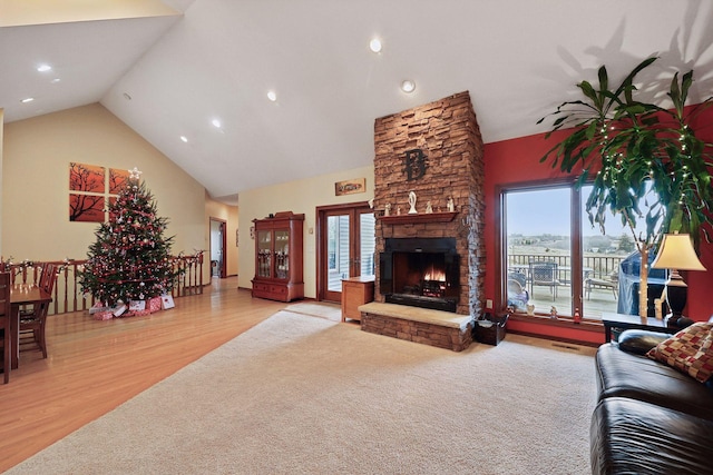 living room featuring light wood-type flooring, high vaulted ceiling, plenty of natural light, and a fireplace