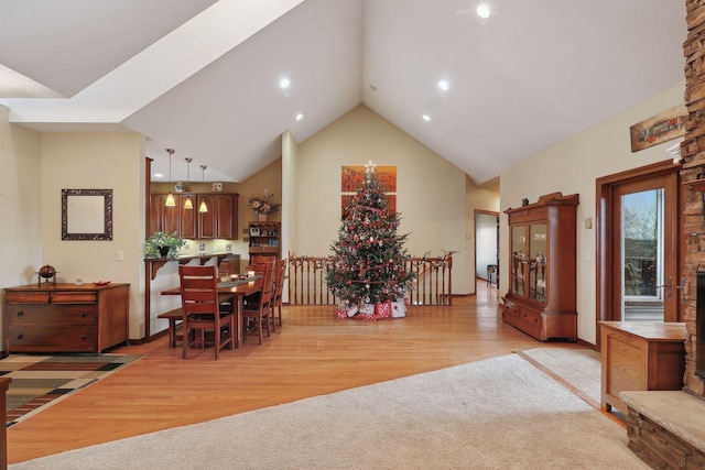 dining area with light hardwood / wood-style floors and high vaulted ceiling