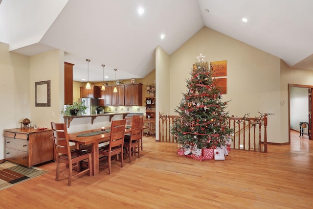 dining space featuring high vaulted ceiling and light wood-type flooring