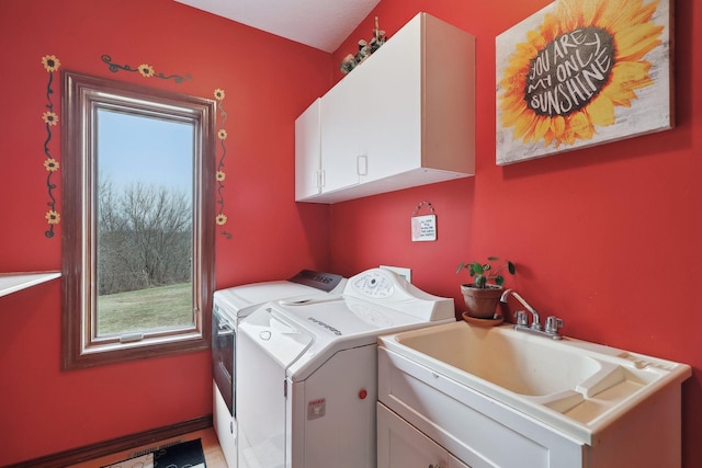 clothes washing area featuring sink, cabinets, and washer and clothes dryer