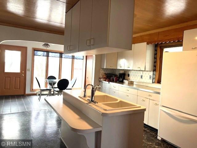 kitchen with sink, kitchen peninsula, white fridge, decorative backsplash, and wood ceiling