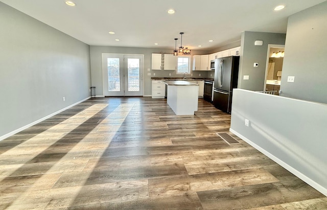 kitchen featuring sink, appliances with stainless steel finishes, white cabinetry, a kitchen island, and decorative light fixtures