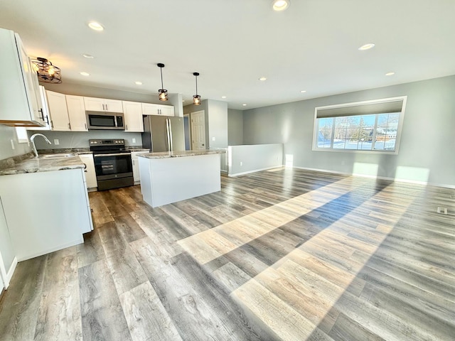 kitchen featuring sink, white cabinetry, decorative light fixtures, a center island, and stainless steel appliances