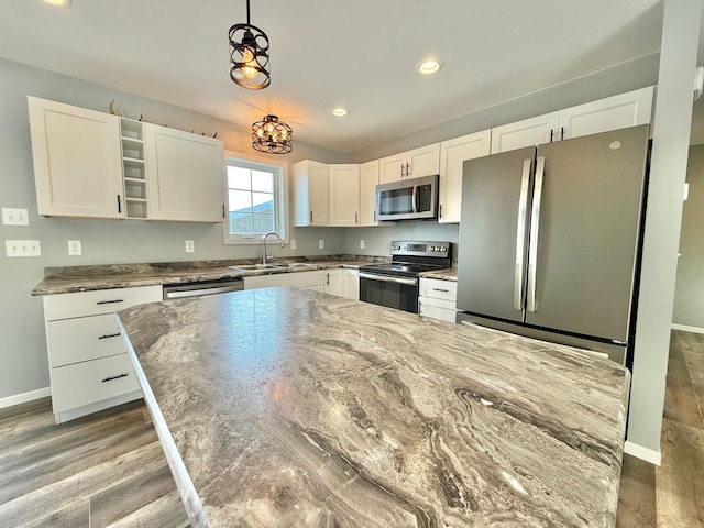 kitchen featuring sink, hardwood / wood-style flooring, appliances with stainless steel finishes, hanging light fixtures, and white cabinets