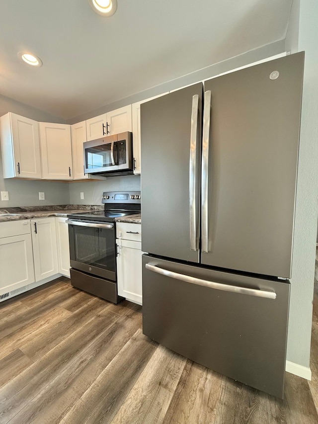 kitchen featuring hardwood / wood-style floors, stainless steel appliances, and white cabinets