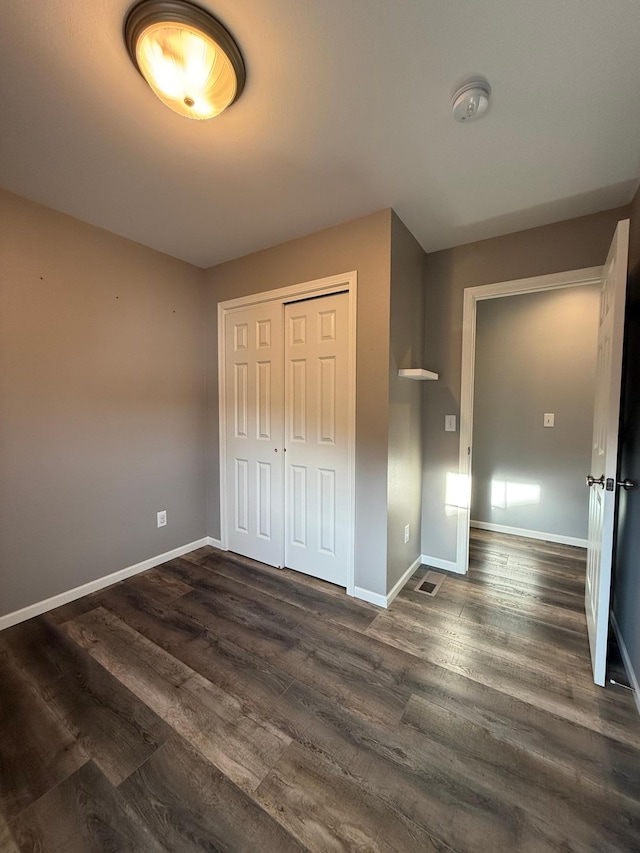 unfurnished bedroom with dark wood-type flooring and a closet