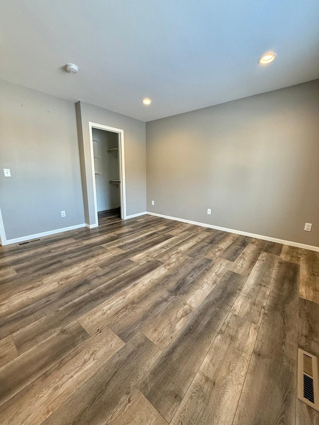 unfurnished bedroom featuring a walk in closet, dark hardwood / wood-style floors, and a closet