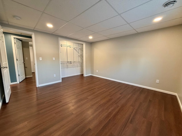 unfurnished bedroom with dark wood-type flooring, a drop ceiling, and a closet