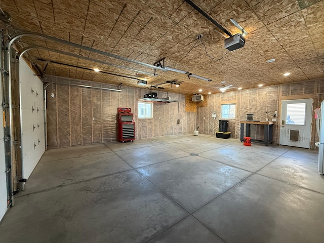 garage featuring a wall mounted air conditioner, a garage door opener, and white refrigerator