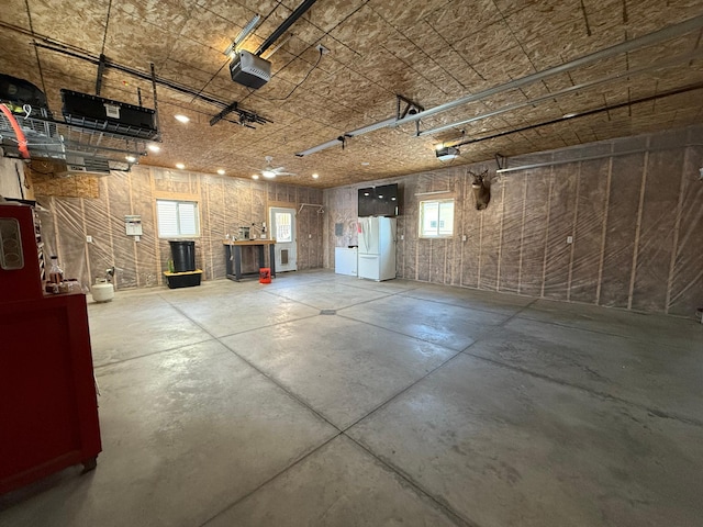 garage featuring a garage door opener, white fridge, and washing machine and clothes dryer