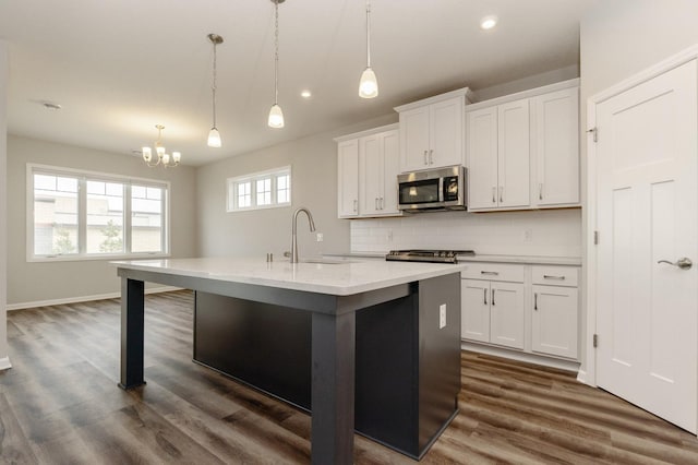 kitchen featuring sink, decorative light fixtures, stainless steel appliances, and a center island with sink